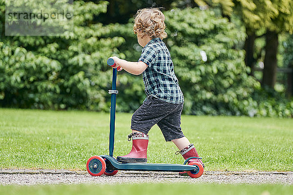 Kleinkind fährt auf einem Roller im Park