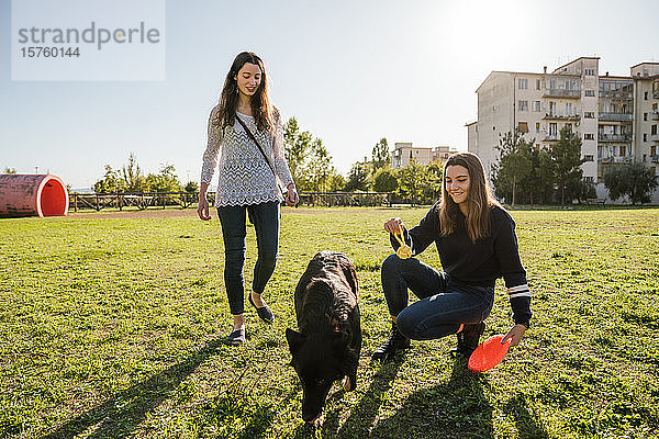 Schwestern spielen mit Hund im Park