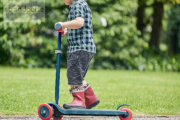 Kleinkind fährt auf einem Roller im Park