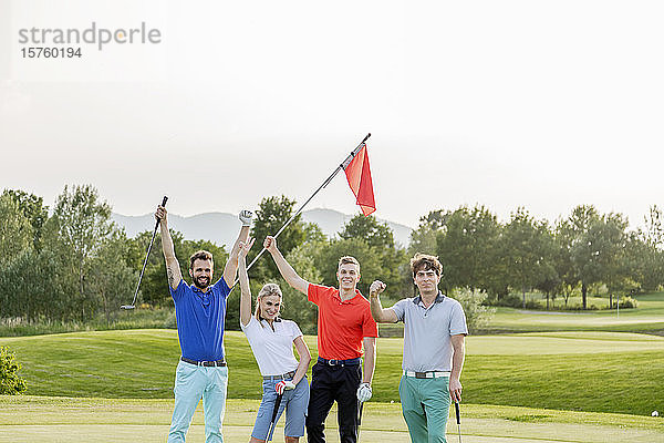 Freunde schwenken Flaggenstock auf dem Golfplatz