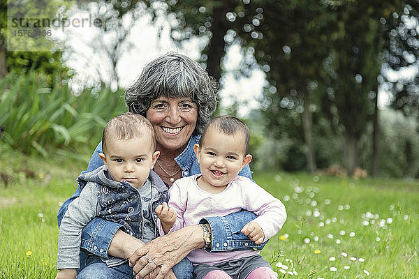 Grossmutter mit zwei Enkelkindern auf dem Schoss im Garten  Florenz  Italien