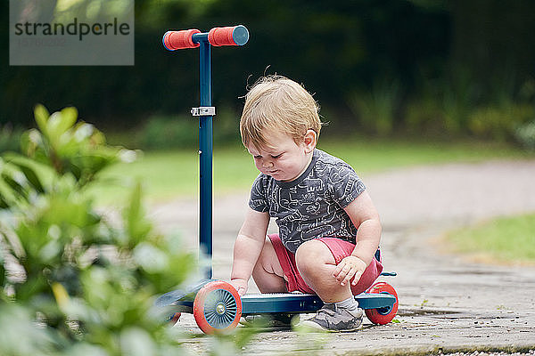 Kleinkind spielt mit Roller im Park