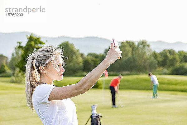 Frau geht mit sich selbst auf den Golfplatz  Freunde spielen Golf im Hintergrund