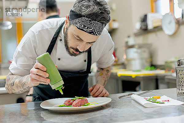 Chefkoch bereitet rohes Fleischgericht in der Küche zu