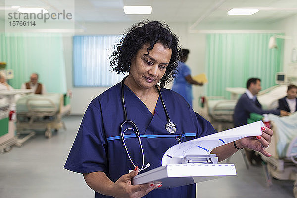 Fokussierte Ärztin bei der Visite  die sich die Krankenakte in einer Krankenhausabteilung ansieht