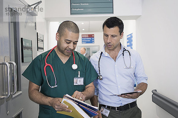 Männlicher Arzt und Chirurg besprechen Krankenakte  machen Visite im Krankenhauskorridor