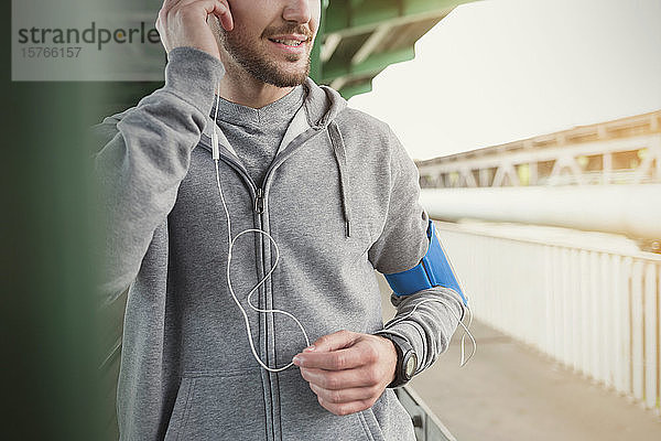 Männlicher Läufer  der mit Kopfhörern und mp3-Player Musik hört