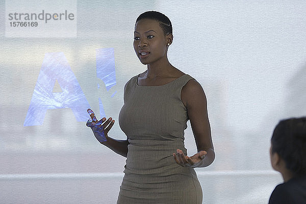 Geschäftsfrau  die eine Besprechung auf einer Projektionsfläche mit AI-Text leitet