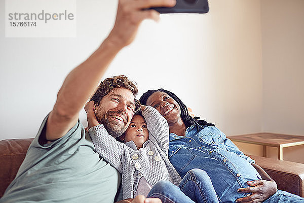 Glückliche schwangere junge Familie nimmt Selfie