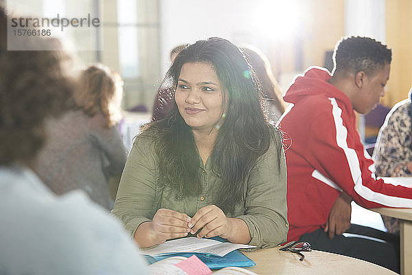 Lächelnde junge Studentin beim Lernen mit Klassenkameraden