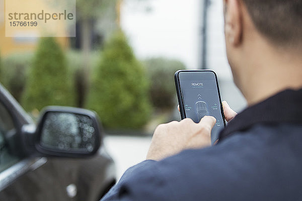 Mann stellt Autoalarm über Smartphone in der Einfahrt ein