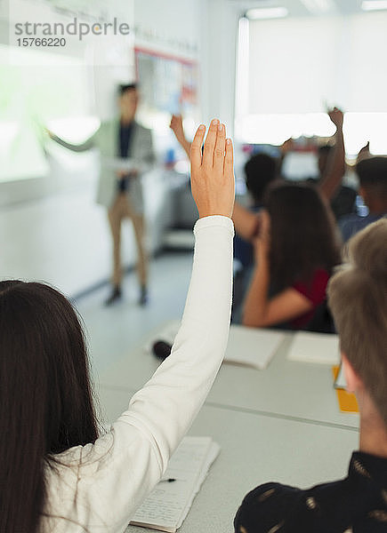 Schülerin der High School hebt die Hand und stellt eine Frage während des Unterrichts im Klassenzimmer