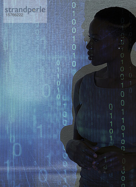 Silhouette einer Geschäftsfrau vor einem binären Code auf einer Projektionsfläche