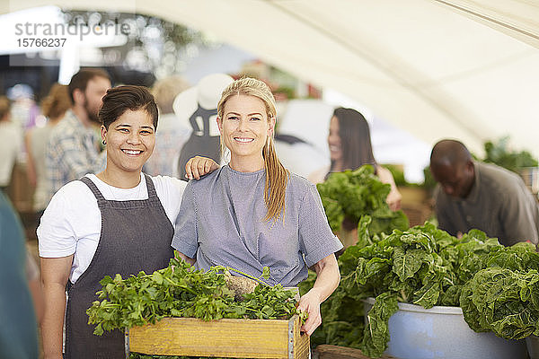 Porträt lächelnde Arbeiterinnen mit Gemüsekiste auf dem Bauernmarkt