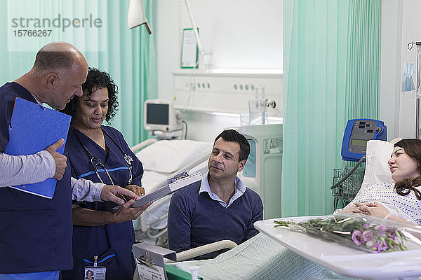 Ärzte mit Krankenblatt bei der Visite  Gespräch mit Ehepaar auf der Krankenstation