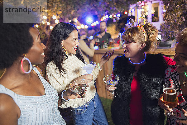 Glückliche Freundinnen trinken Cocktails auf einer Party
