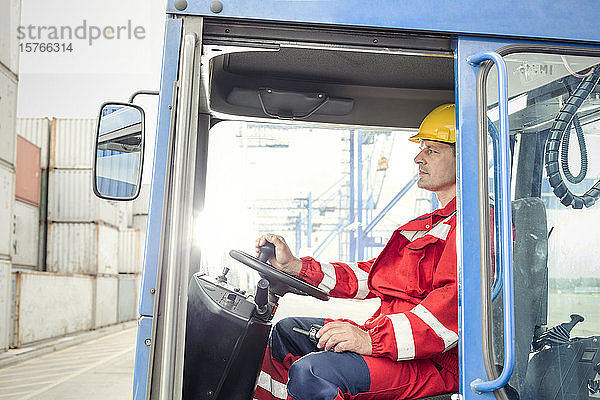 Hafenarbeiter  der einen Gabelstapler für Frachtcontainer in einer Werft bedient