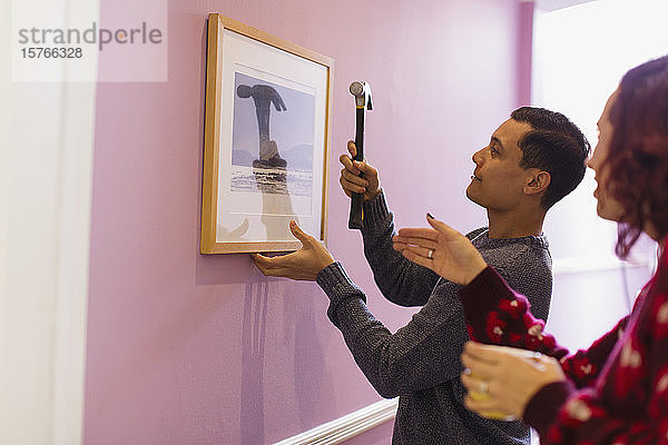 Ehepaar renoviert  hängt gerahmtes Foto an die Wand