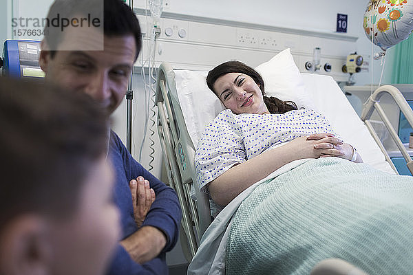 Lächelnder Patient bei einem Besuch mit seiner Familie im Krankenhauszimmer