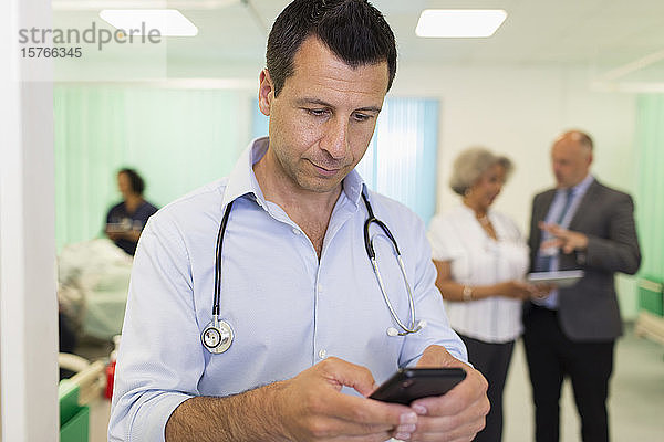 Männlicher Arzt  der ein Smartphone in einer Krankenstation benutzt