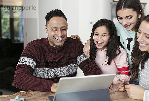 Glückliche Familie mit digitalem Tablet am Tisch