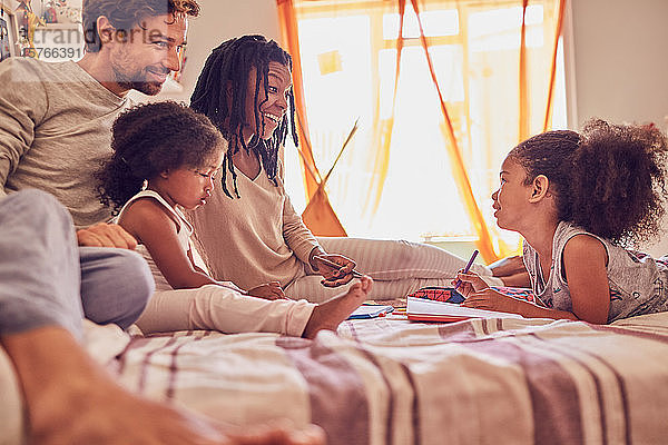 Junge Familie beim Malen auf dem Bett