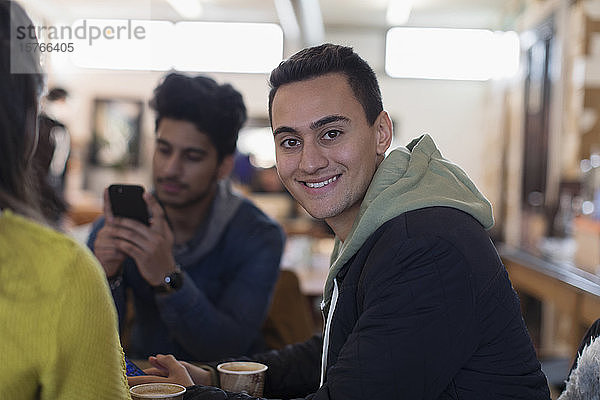 Porträt eines selbstbewussten jungen Mannes  der mit Freunden in einem Café abhängt