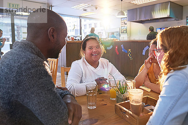 Glückliche junge Frau mit Down-Syndrom in einem Café mit Freunden