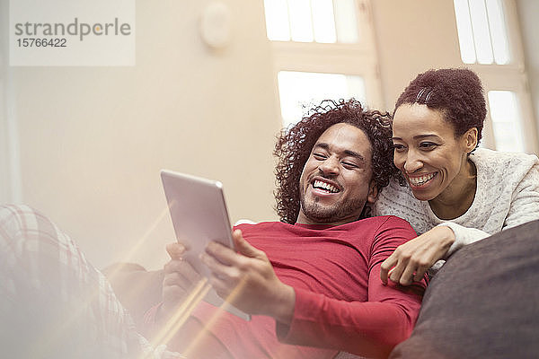 Glückliches Paar benutzt digitales Tablet auf dem Sofa