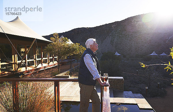 Gelassener älterer Mann entspannt sich auf dem sonnigen Balkon einer Safari-Lodge