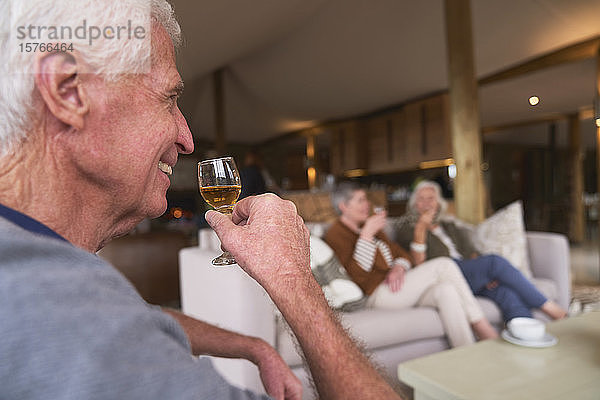 Glücklicher älterer Mann  der mit Freunden im Hotel ein Getränk trinkt