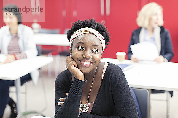 Lächelnde  selbstbewusste junge Studentin einer Volkshochschule im Klassenzimmer