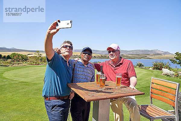 Männliche Freunde trinken Bier und machen ein Selfie auf der Terrasse des Golfplatzes