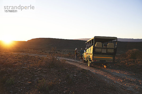 Safari-Geländewagen und Touristen bei Sonnenuntergang am Straßenrand Südafrikas