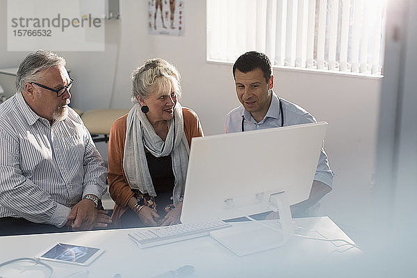 Arztgespräch mit einem älteren Ehepaar am Computer in einer Arztpraxis