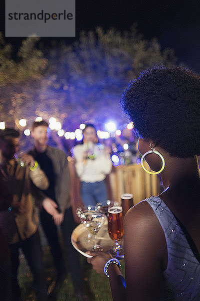 Junge Frau serviert Cocktails auf einer Gartenparty