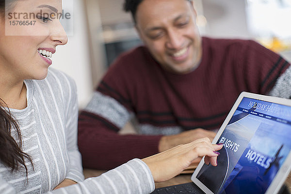 Glückliches Paar plant Urlaub auf digitalem Tablet