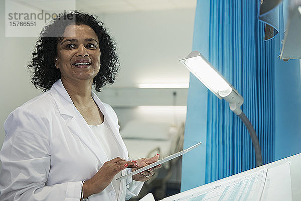 Lächelnde Ärztin mit digitalem Tablet im Krankenhauszimmer