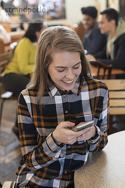 Junge Frau benutzt Smartphone in einem Cafe