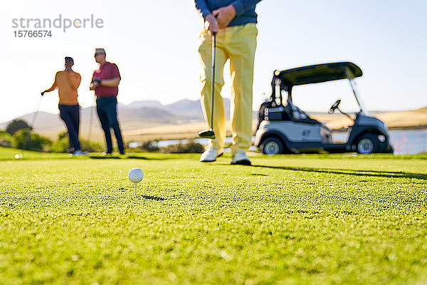Männlicher Golfer bereitet sich auf den Abschlag auf einem sonnigen Golfplatz vor