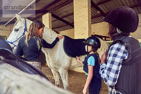 Ausbilderin hilft Mädchen bei der Vorbereitung auf das Reiten