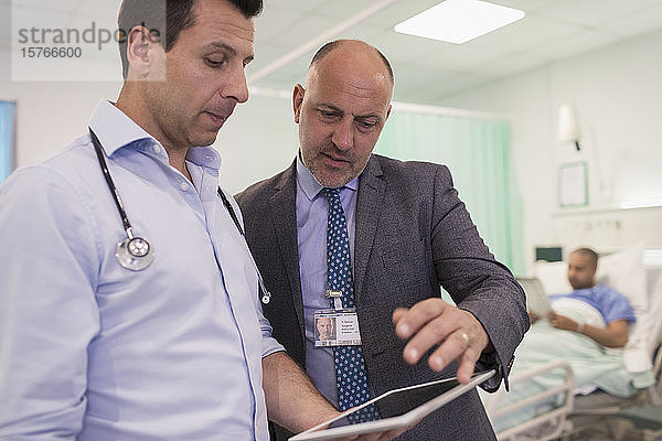 Männliche Ärzte mit digitalem Tablet bei der Visite  Beratung im Krankenhauszimmer