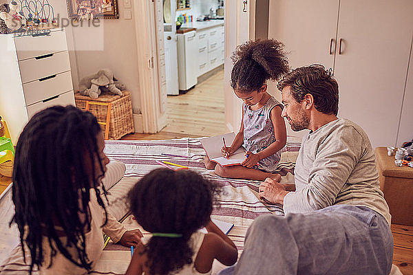 Junge Familie beim Malen auf dem Bett