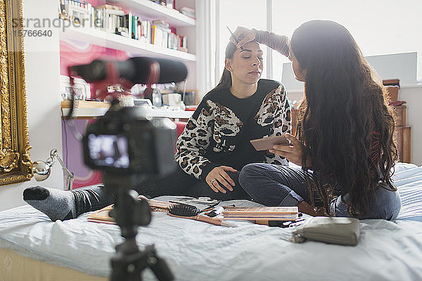 Teenager-Freundinnen führen einen Vlog über das Auftragen von Make-up im Bett
