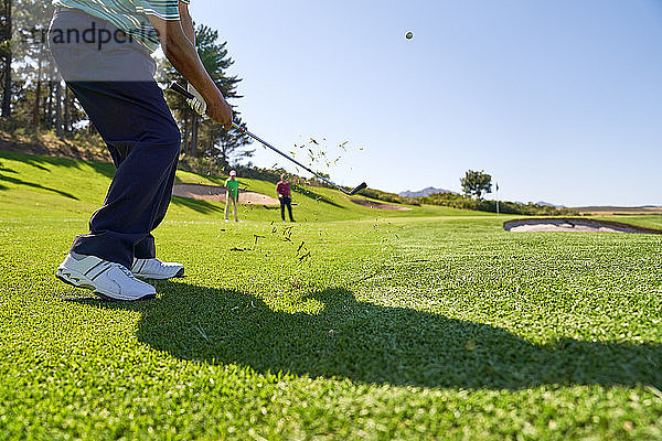 Männlicher Golfer bei einem Schlag auf dem sonnigen Golfplatz