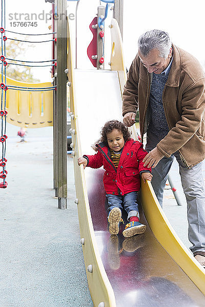 Großvater spielt mit Kleinkind Enkel auf Spielplatz Rutsche