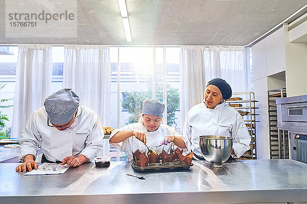 Koch und Schüler mit Down-Syndrom backen Muffins in der Küche