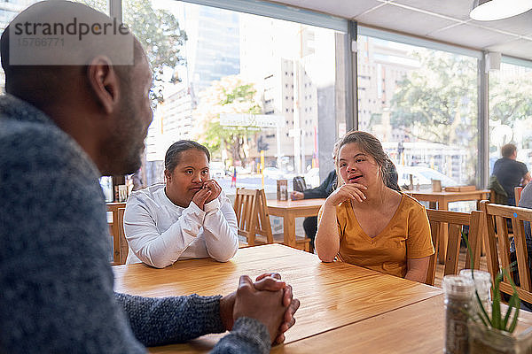 Mentorin und junge Frau mit Down-Syndrom im Gespräch im Café