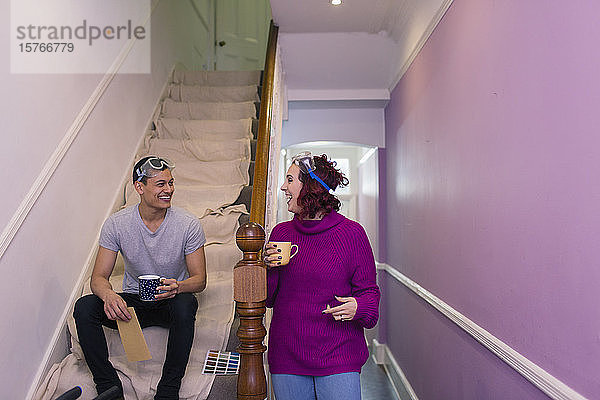 Glückliches Paar beim Renovieren  Kaffeetrinken auf der Treppe