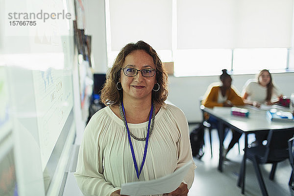 Porträt einer selbstbewussten Gymnasiallehrerin vor einer Projektionsfläche im Klassenzimmer